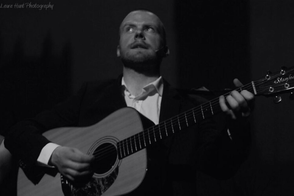 A black and white photograph of Dave Flynn playing guitar