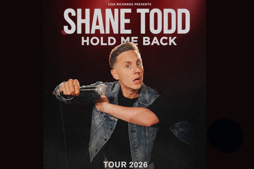 Shane Todd with a microphone against a black background  Shane Todd with a microphone against a black background