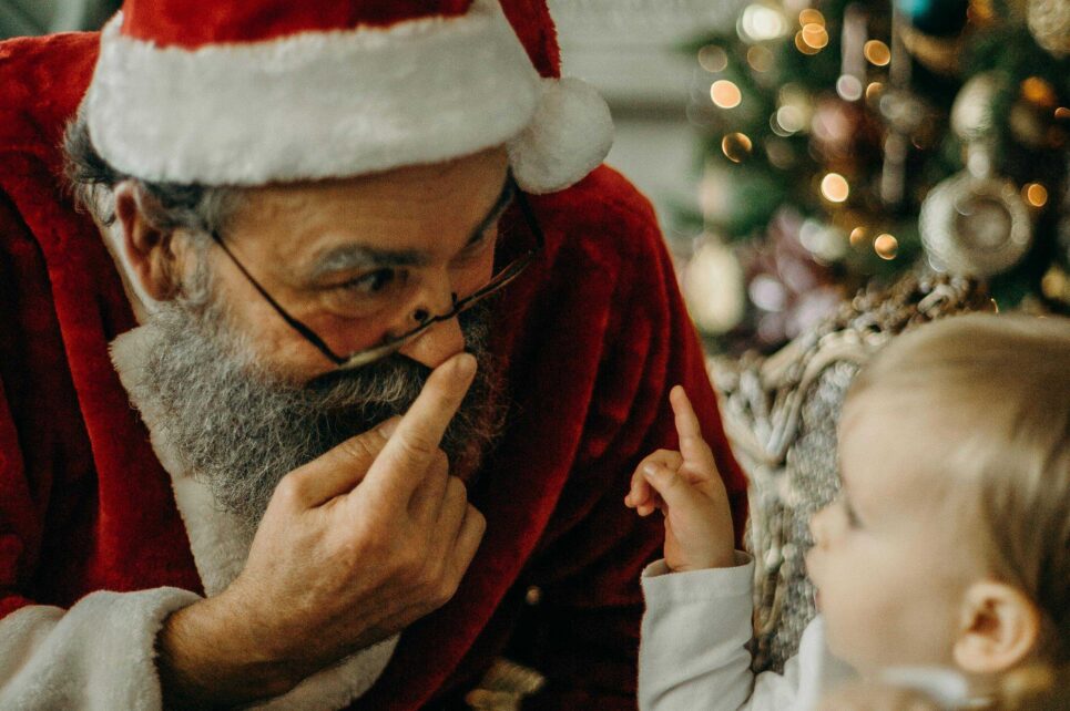 Santa Clause touching his nose and a baby pointing at him