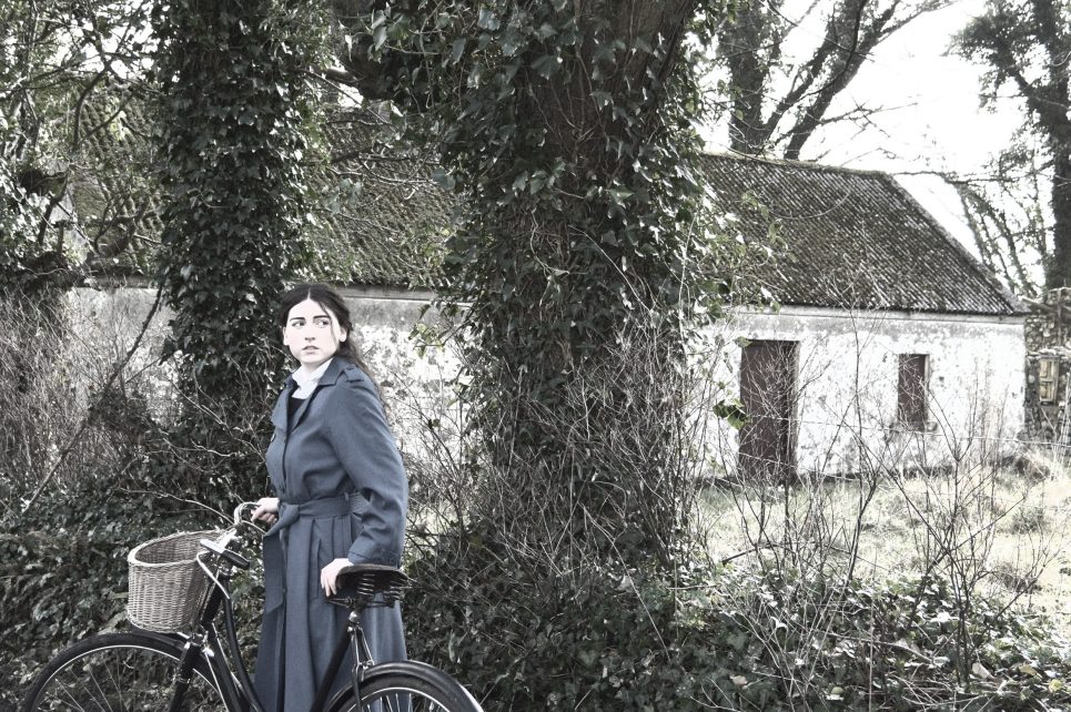 Woman with bicycle in front of traditional Irish cottage