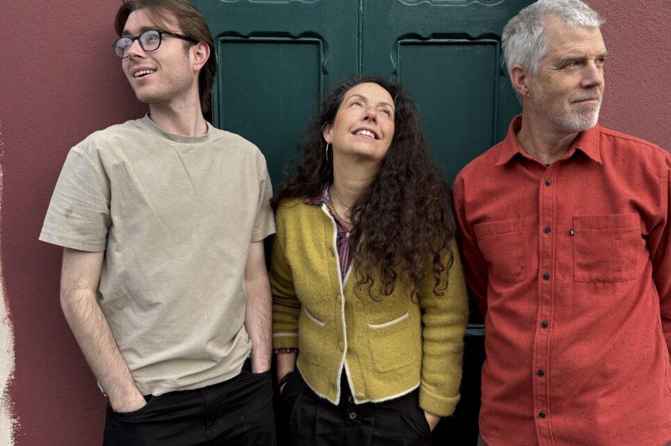 Picture of three people staring in three different direction against a green door