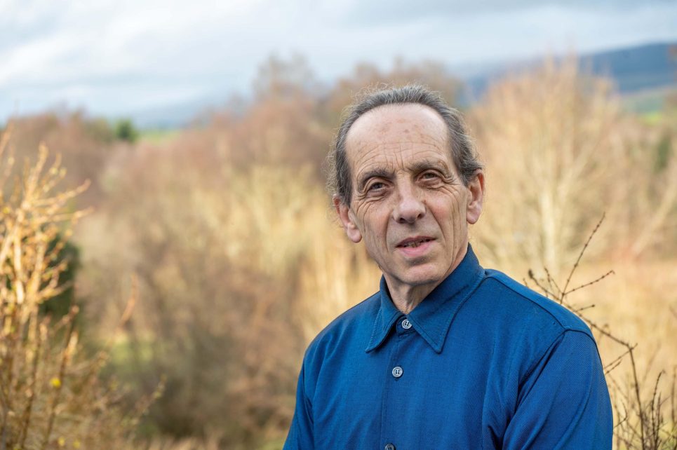 Photo of man in a field wearing a blue shirt