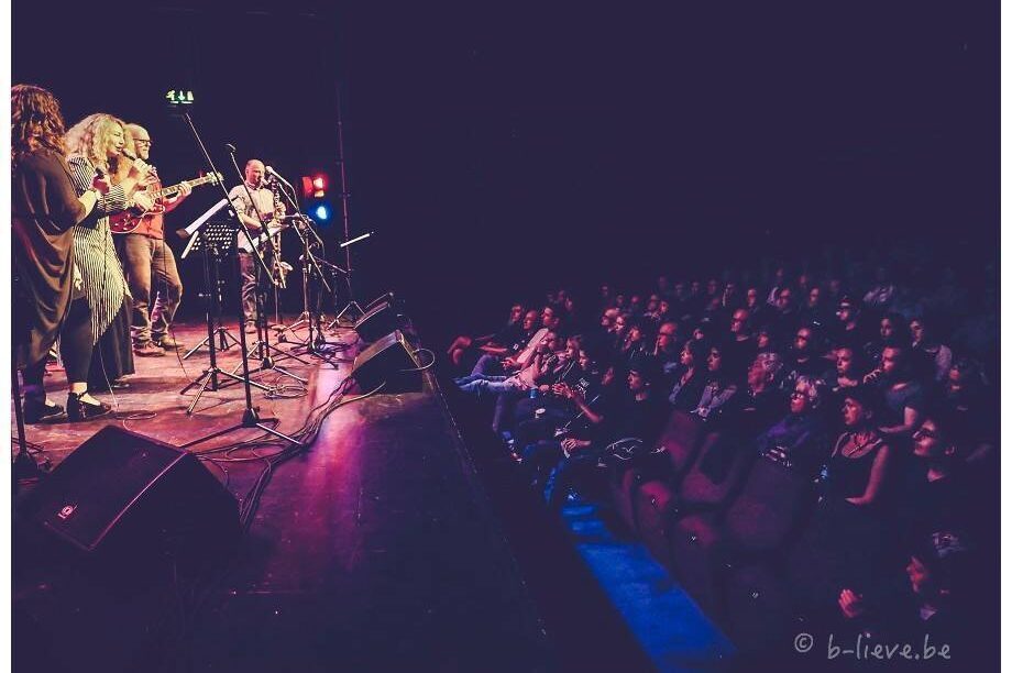 A photograph of jazz performers on stage being watched by a full audience.