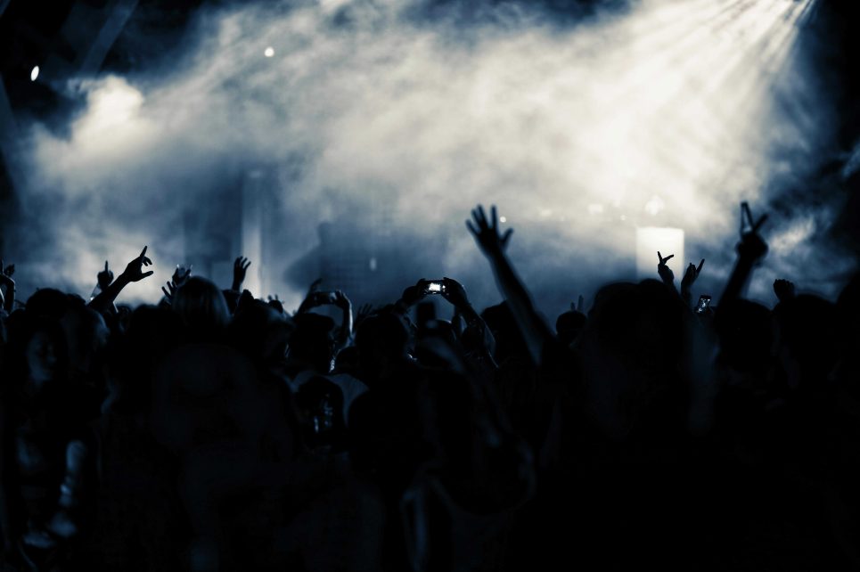A photograph of a lit stage filled with smoke and a silhouette of a crowd in front of it A photograph of a lit stage filled with smoke and a silhouette of a crowd in front of it