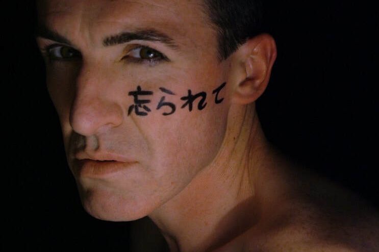 Close up image of performer Pat Kinevane with a tattoo of oriental text on his face Close up image of performer Pat Kinevane with a tattoo of oriental text on his face