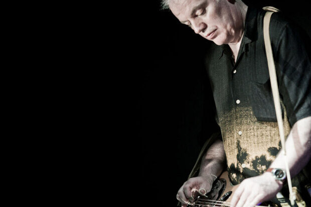 Guitarist playing against a black background