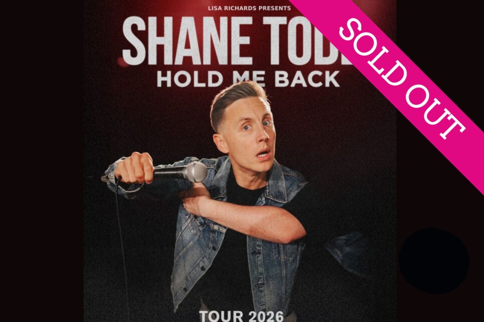 Shane Todd with a microphone against a black background Shane Todd with a microphone against a black background