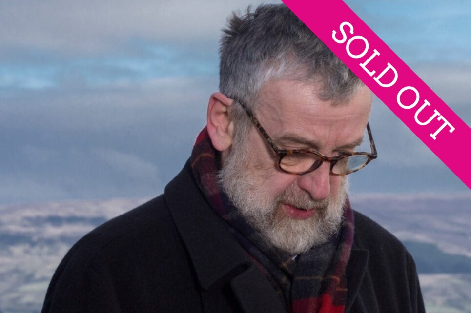 Man with glasses staring at the ground against a blue sky