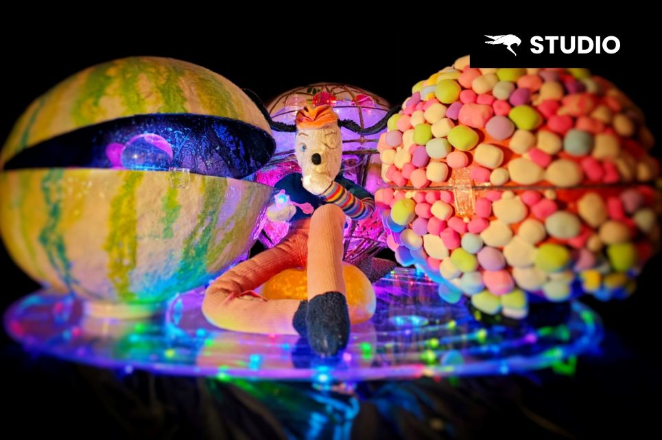 Colourful teddy bear sitting next to colourful plastic orbs