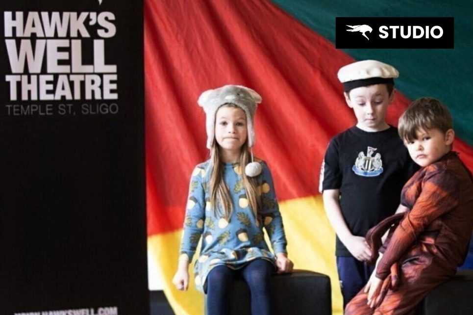 Kids dressed up in front of a colorful flag and next to a Hawk's Well banner Kids dressed up in front of a colorful flag and next to a Hawk's Well banner