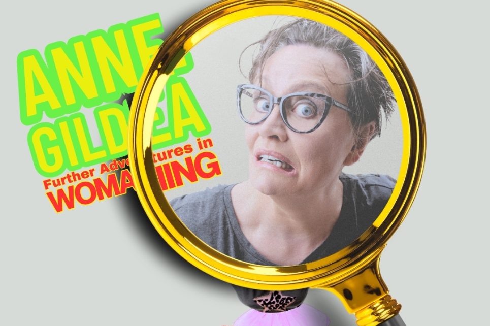Artist Anne Gildea making a funny face under a massive magnifying glass 